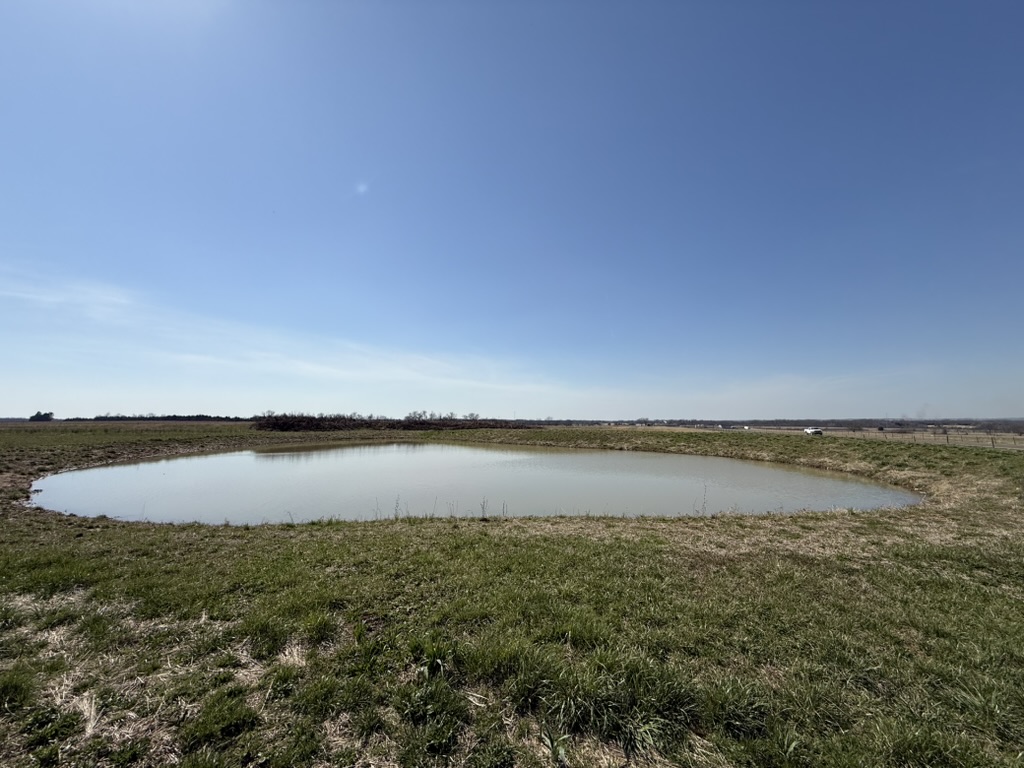 Prescott farm pond with hay bales and blue sky reflected in water